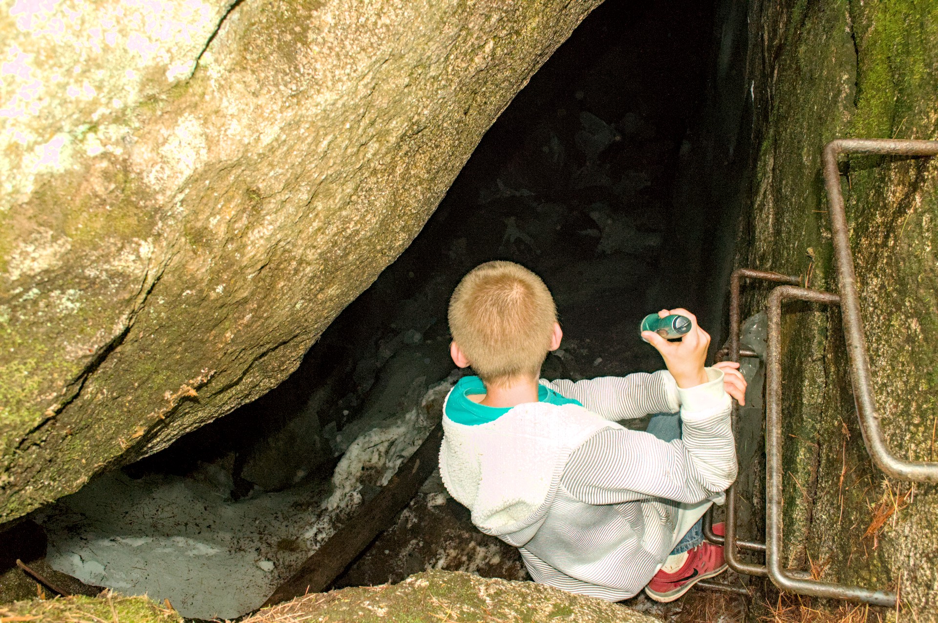Headfirst into the ice caves at Sandy Stream Pond — the entrance is tight and the railing is there for good reason