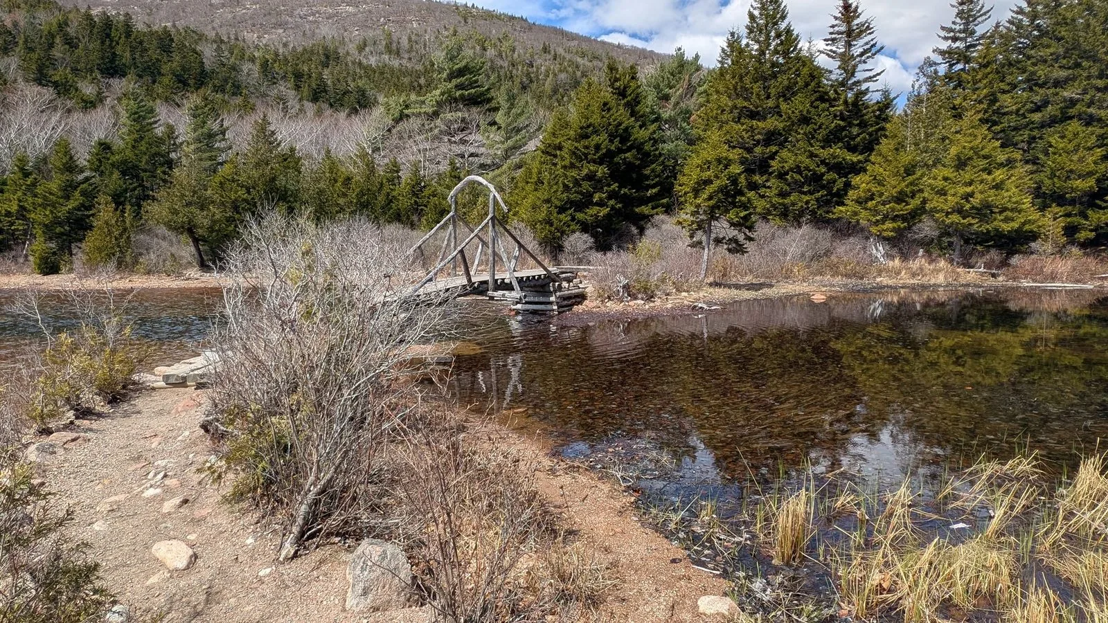 The stone inlet bridge on the north end of Jordan Pond — the two Bubbles visible above the treeline ahead